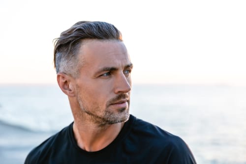 close-up portrait of handsome adult man with grey hair looking away on seashore-img-blog