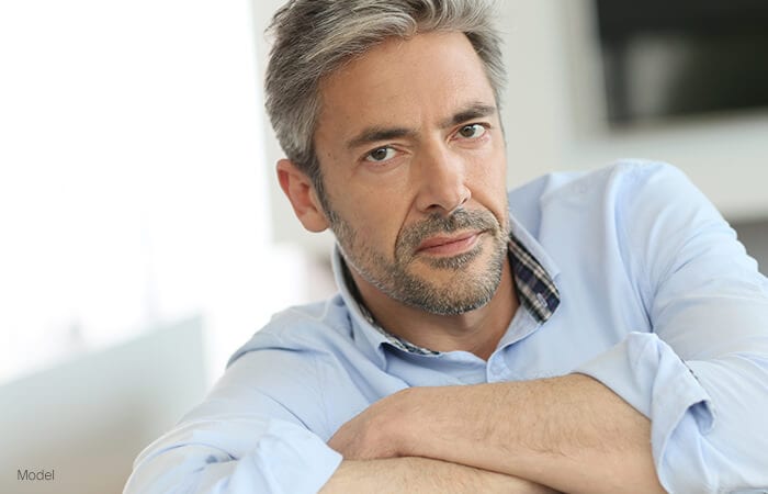 male model serious stare wearing a light blue shirt for revision facelift