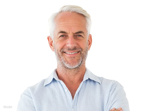 male model facing forward with gray hair and beard, wearing a white polo shirt for stemcell enhancement facelift