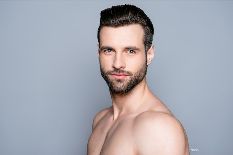 Bust of a young man with a beard against a gray background