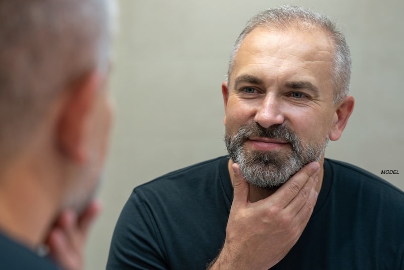 Handsome middle-age man looking at himself in the mirror