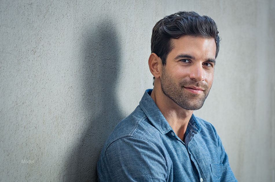 Young man poses against a grey background.